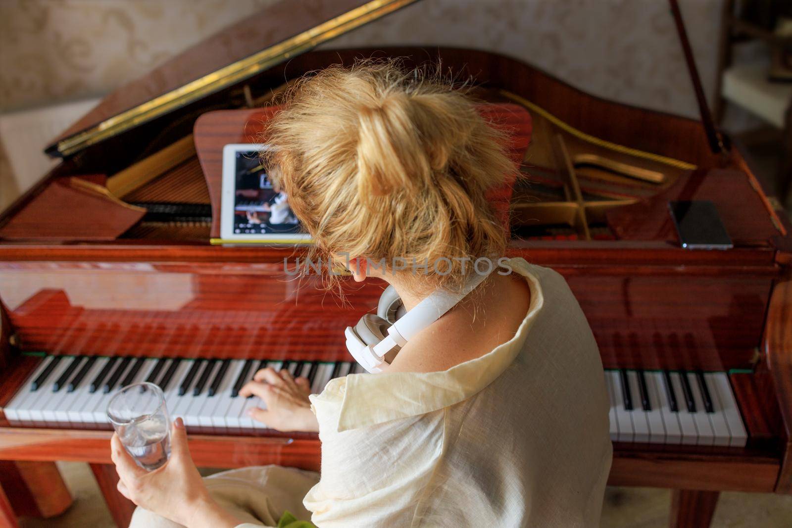 a young girl watches a teaching video on playing the piano, wants to learn song by Ramanouskaya