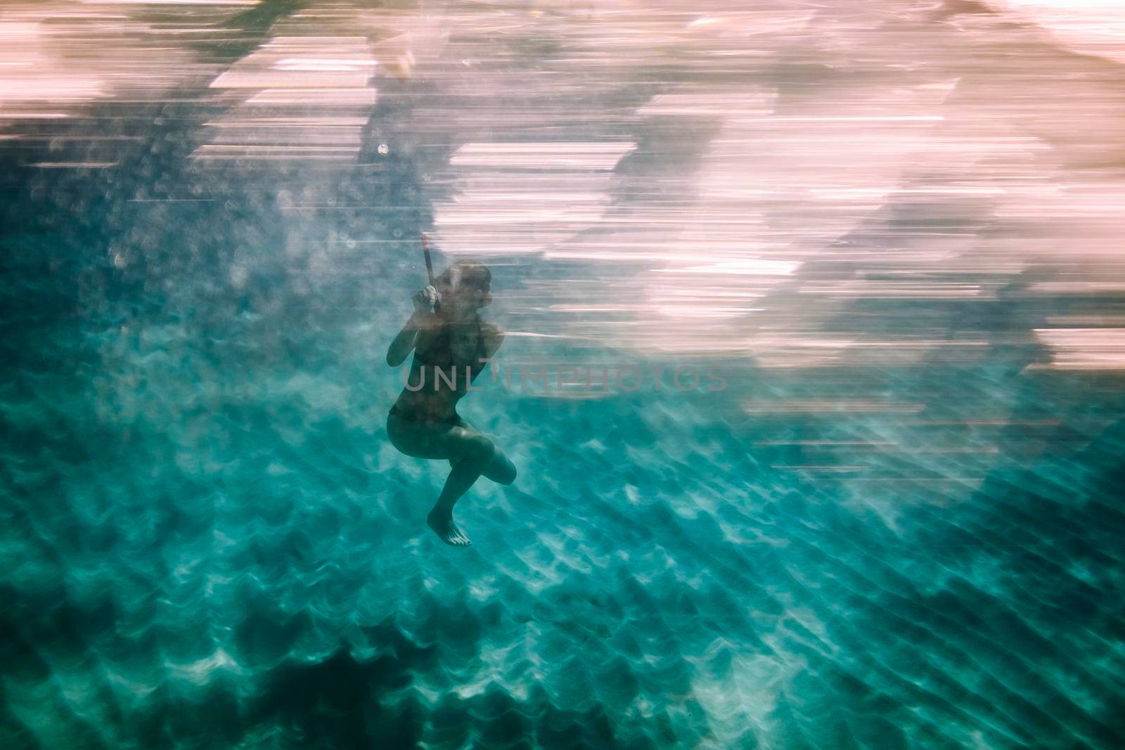 Woman diving into blue water in the sea. Underwater photography.