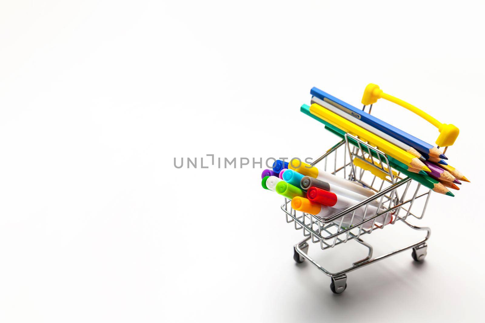Shopping trolley filled with multicolored school supplies isolated on a white background. Back to school concept