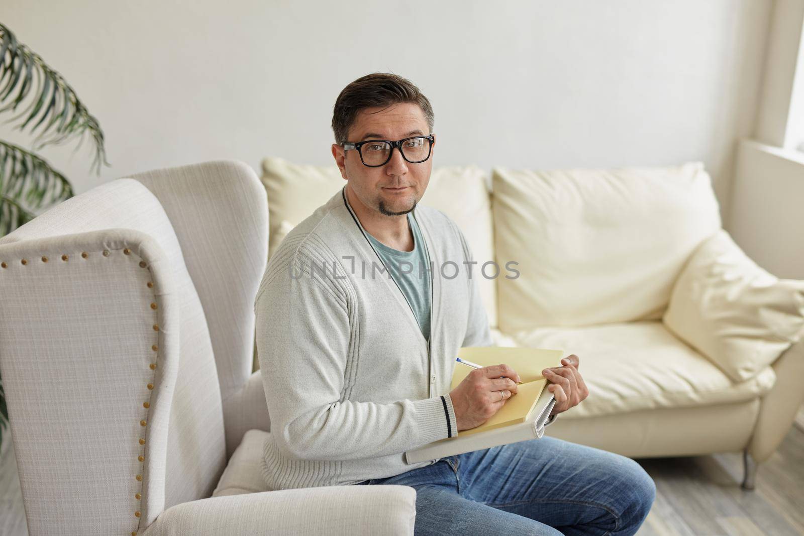 Waiting for patient. Friendly psychologist sitting with clipboard, in office, empty space