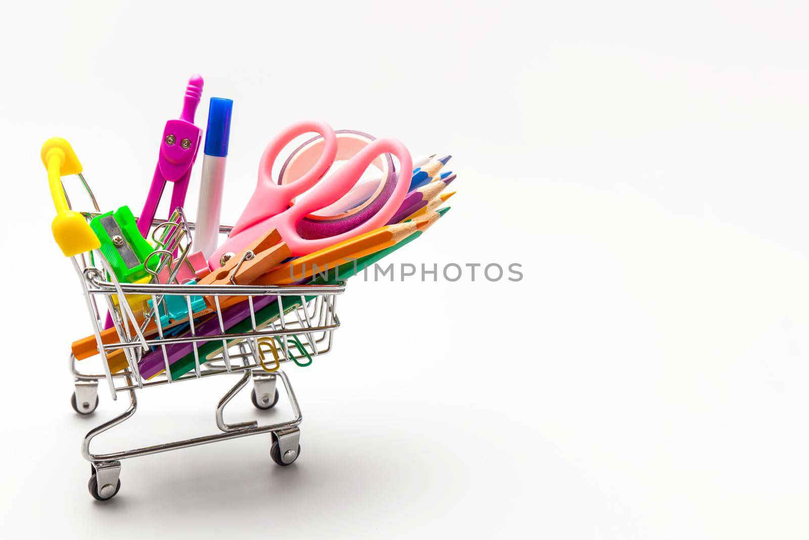Shopping trolley filled with multicolored school supplies isolated on a white background. Back to school concept