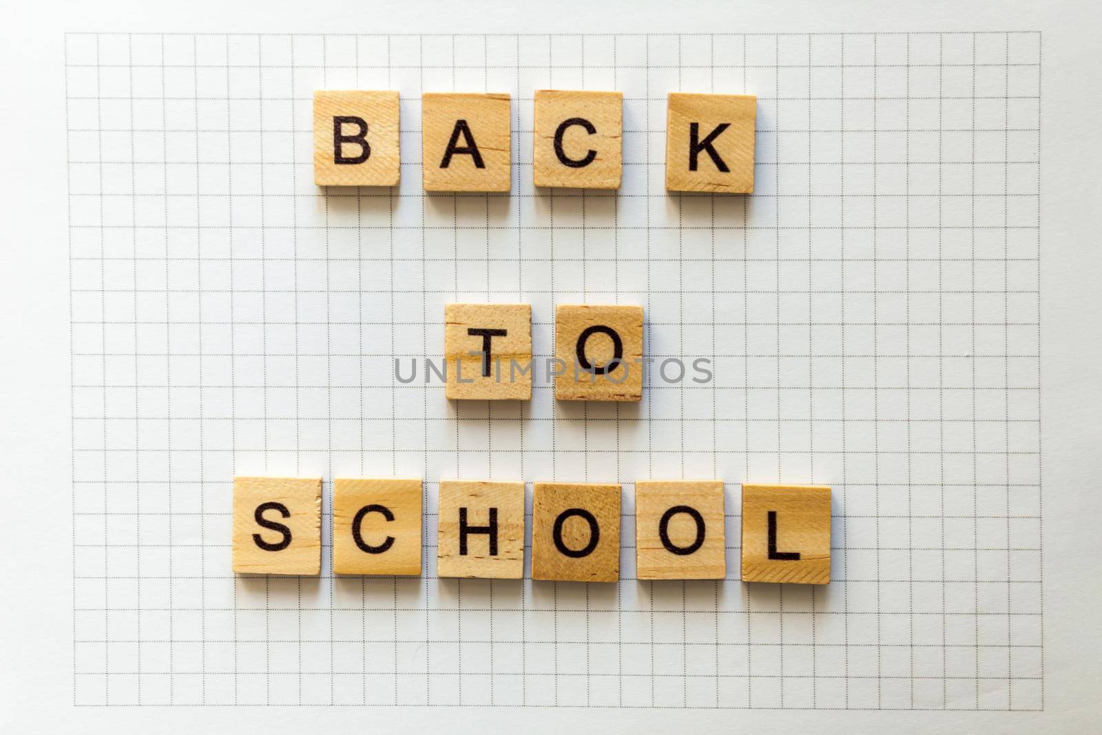 the inscription BACK to SCHOOL in wooden letters with shadows on office notebook sheet