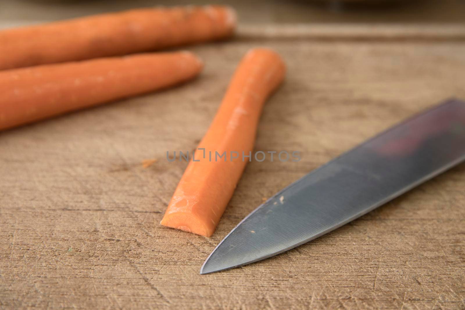 Knife skills cutting a carrot: carrot and chef's knife on cutting board.