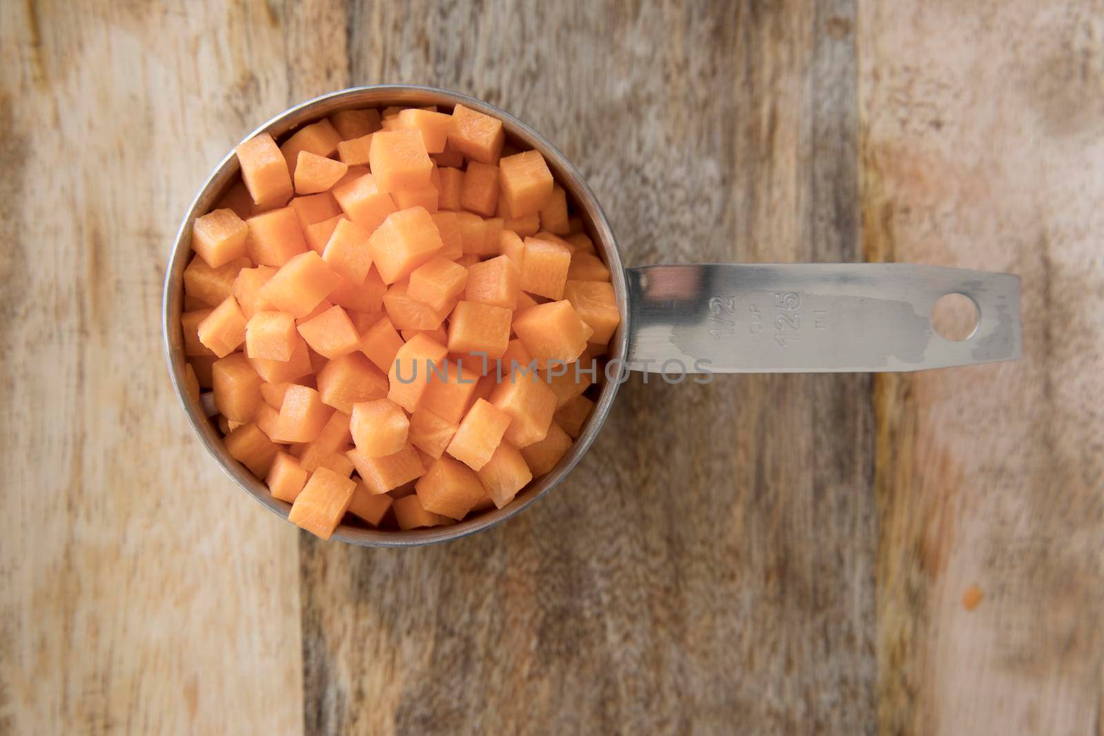 Carrots diced and in a metal measuring cup
