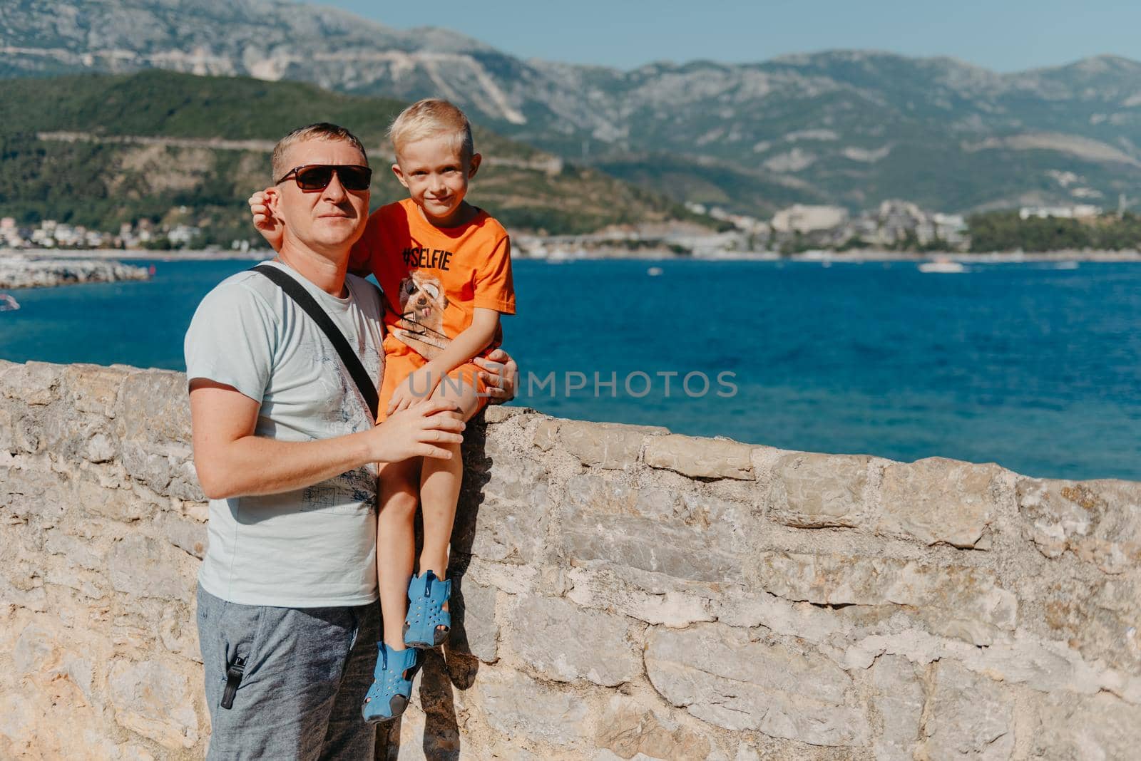 Cute family are having fun on the beach. Father and child against the background of the blue sea and sky. Travel, active lifestyle, vacation, rest concept. a man with a child on the shore. tourists on the shore of Budva, Montenegro.