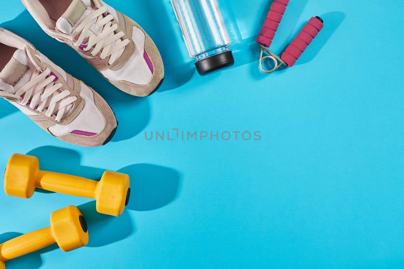 Female sport shoes and equipment on a bright blue background. Active lifestyle, body care concept. Top view. Copy space. Flat lay. Still life