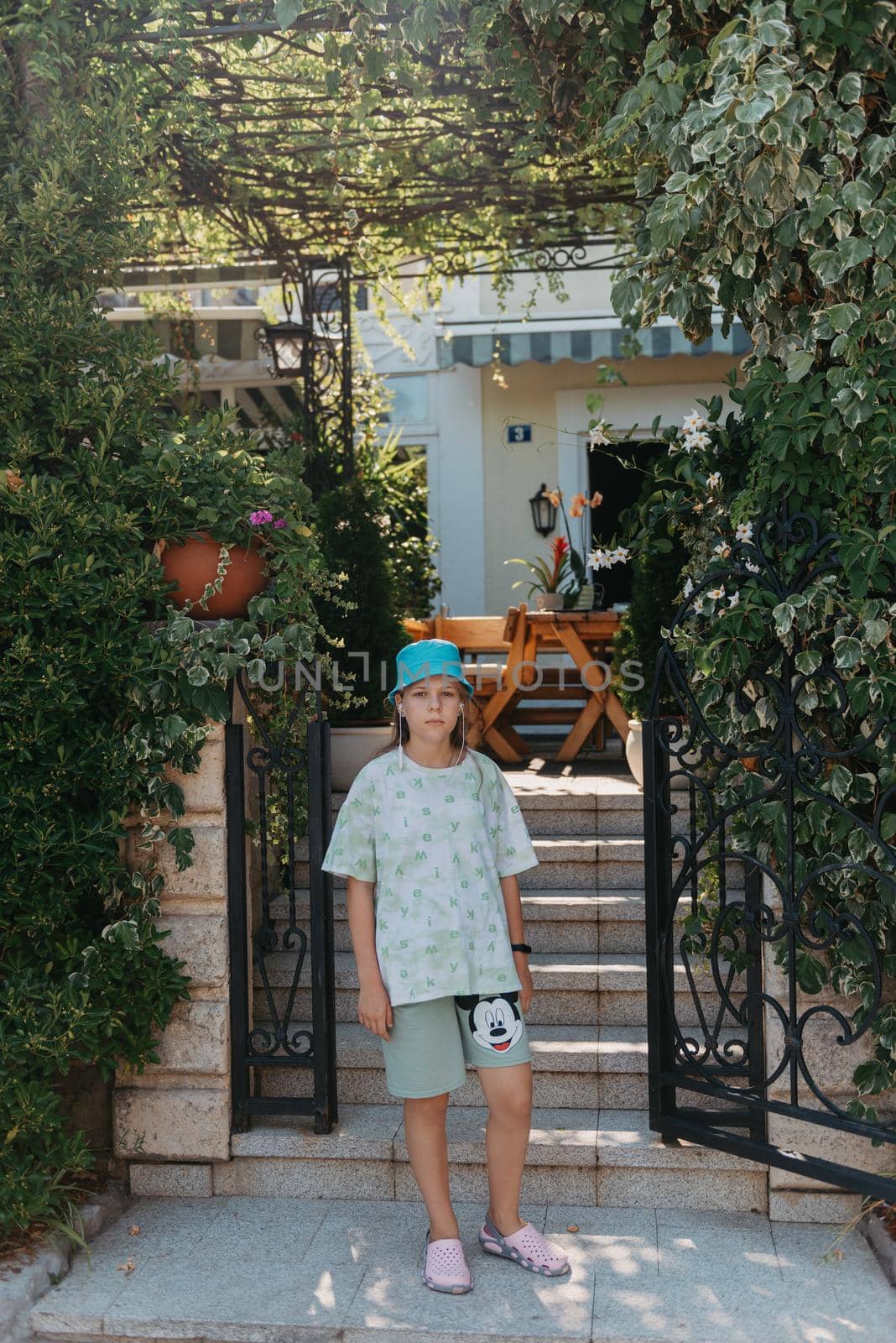 Girl standing in the entrance to the back yard. A beautiful cozy courtyard, a girl stands near the entrance to a beautiful courtyard.