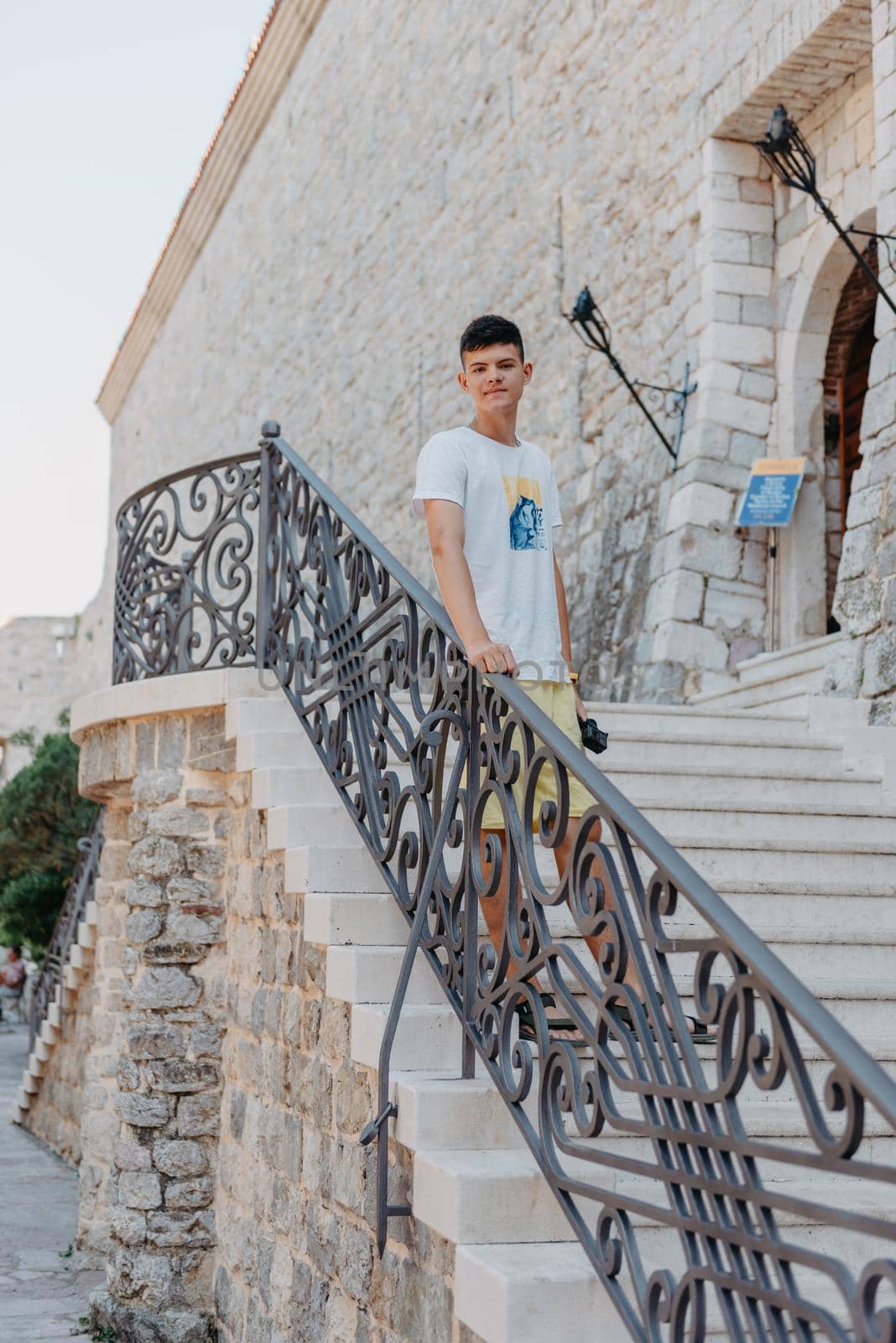 A handsome young man standing and smiling happily in the background of urban buildings. Forty years old caucasian tourist man outdoor near old city buildings - summer holiday.