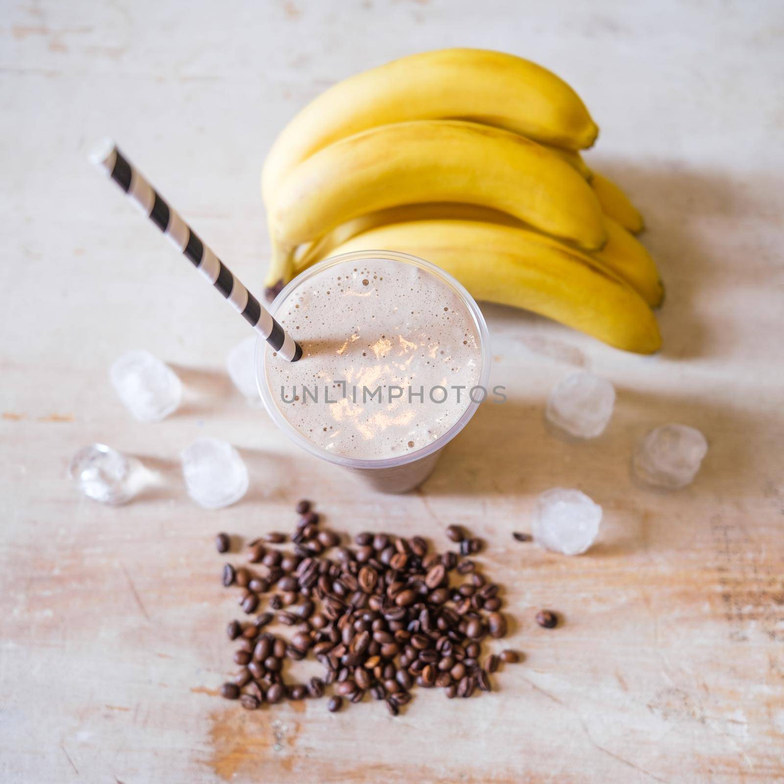 Ice coffee with banana flavor on table with ingredients around.