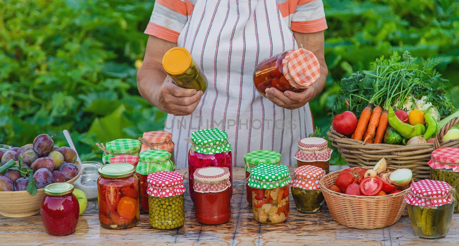 Senior woman preserving vegetables in jars. Selective focus. Food.