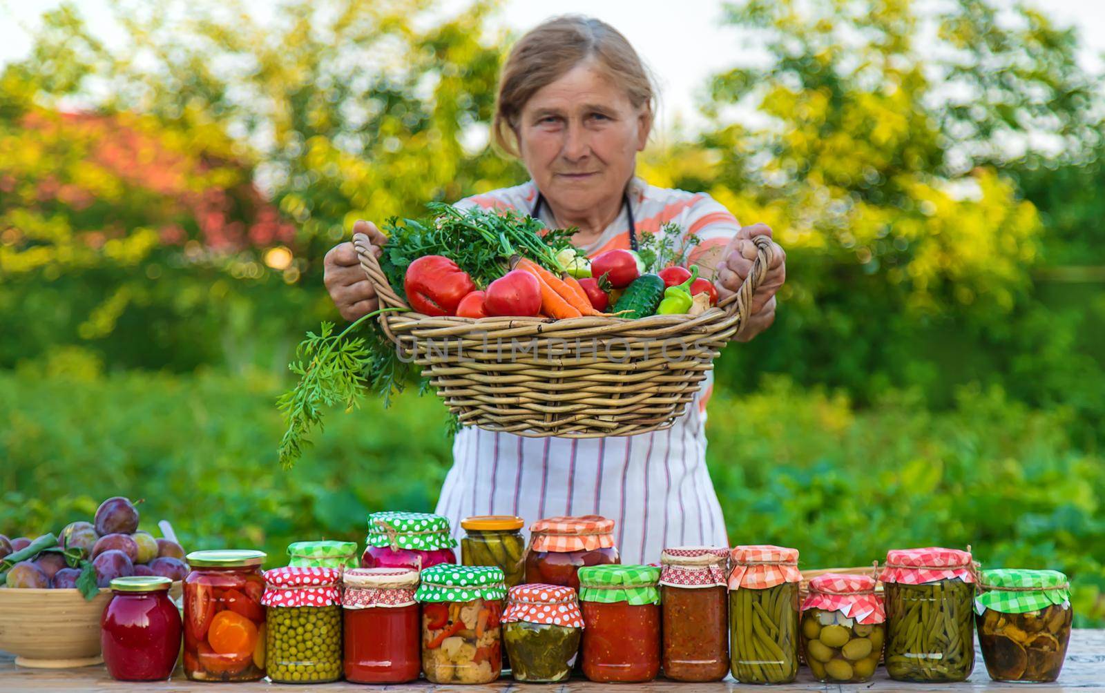 Senior woman preserving vegetables in jars. Selective focus. Food.