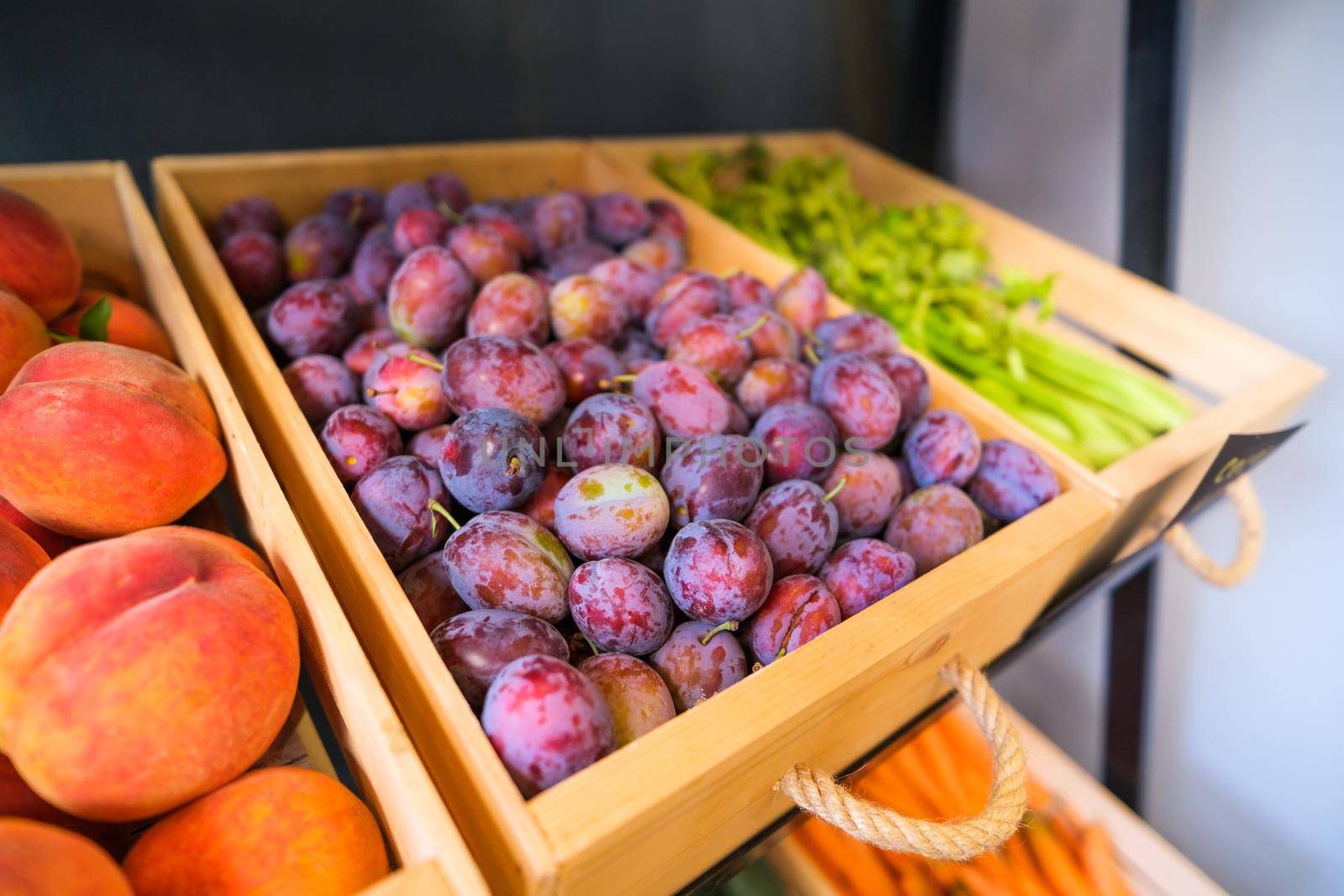 Healthy fruit and vegetables in grocery shop. Close up of basket with plums in supermarket.