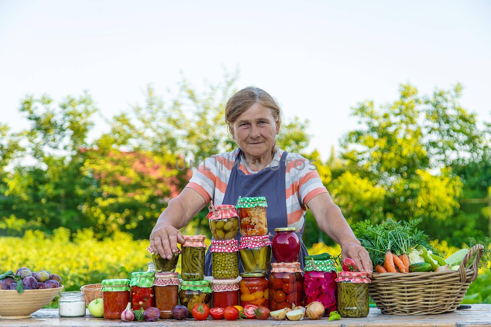 Senior woman preserving vegetables in jars. Selective focus. Food.