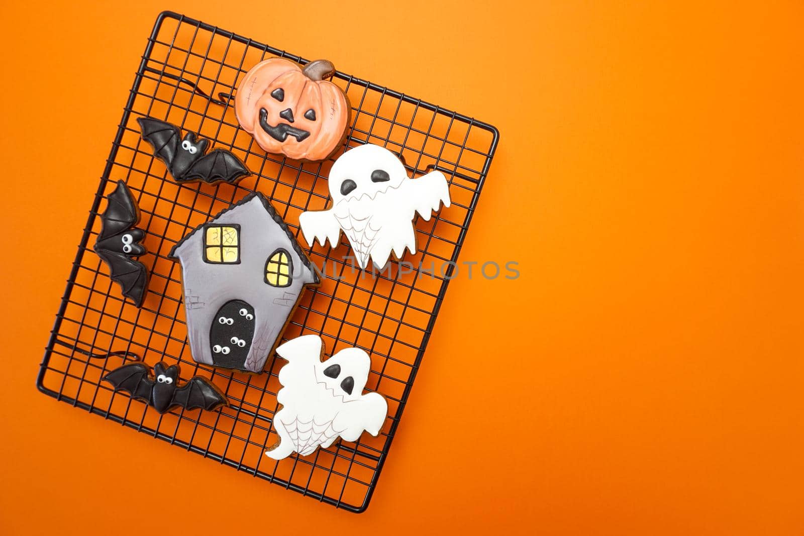 Gingerbread cookies for Halloween celebration are on an orange background by Spirina