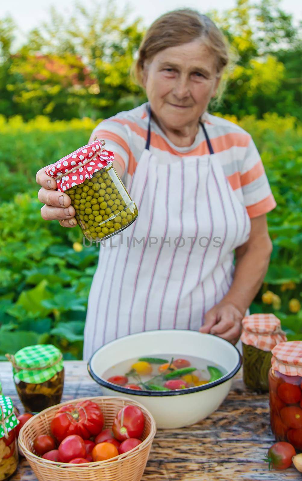 Senior woman preserving vegetables in jars. Selective focus. Food.