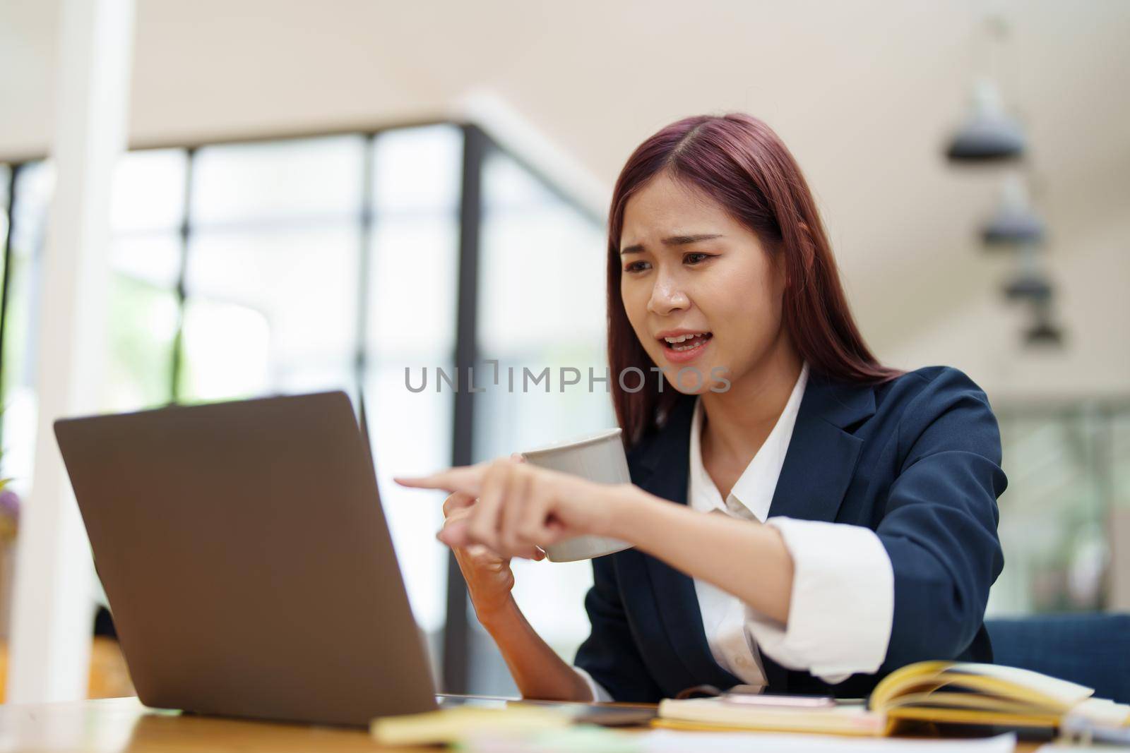 Asian businesswoman taking a coffee break while using a computer by Manastrong