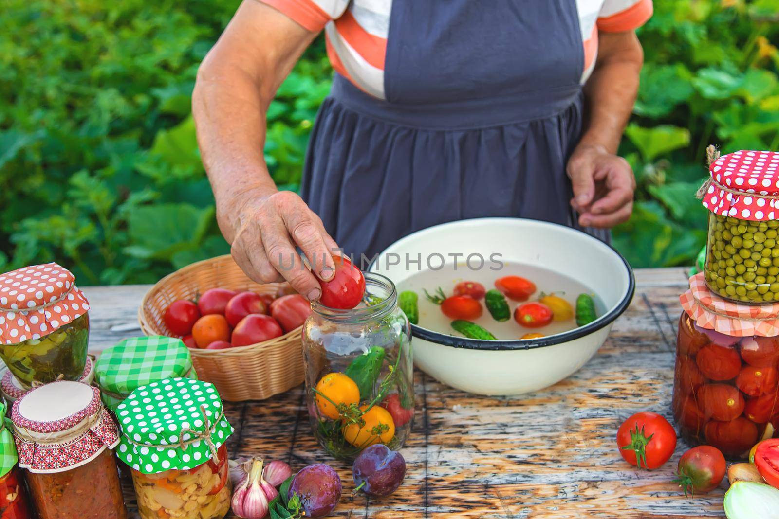 Senior woman preserving vegetables in jars. Selective focus. Food.