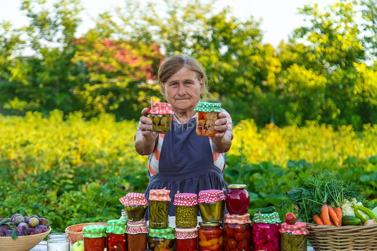 Senior woman preserving vegetables in jars. Selective focus. Food.
