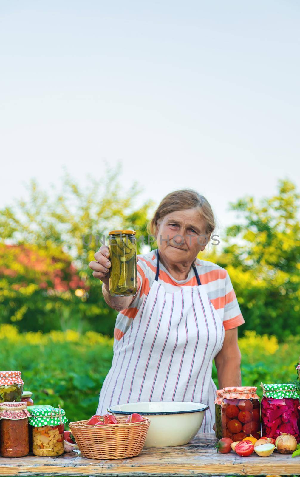 Senior woman preserving vegetables in jars. Selective focus. Food.