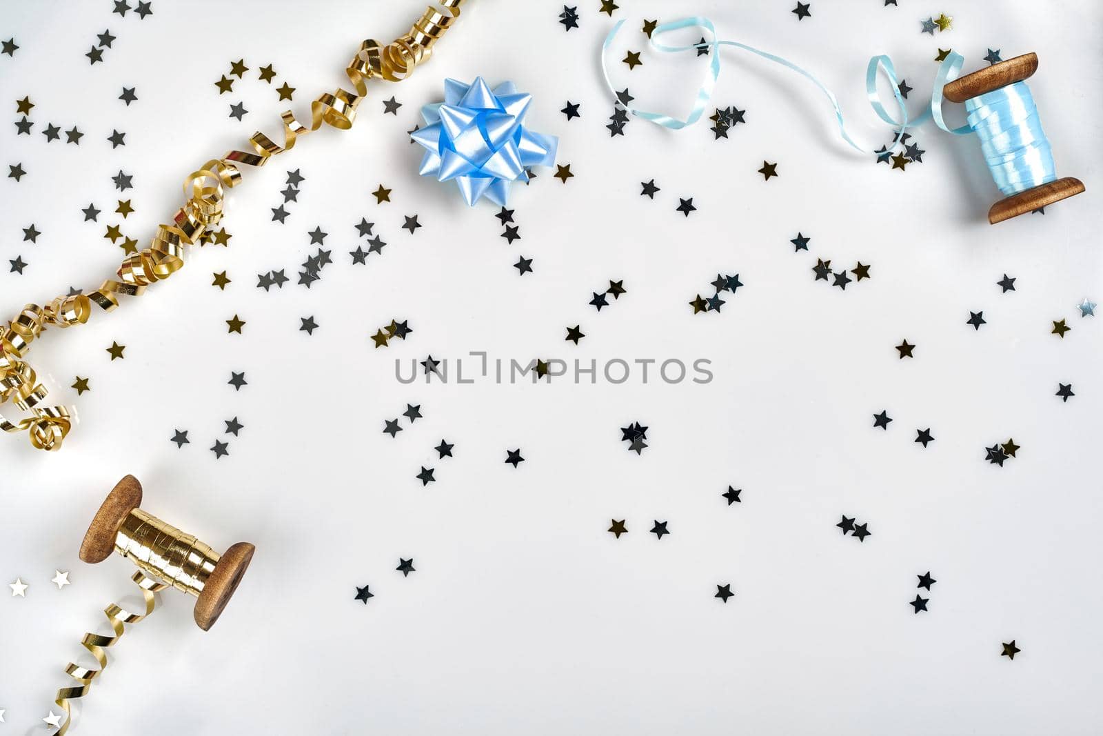 Delicate wavy ribbons and metallic star shaped confetti isolated on white background. Christmas holidays decoration concept. by nazarovsergey
