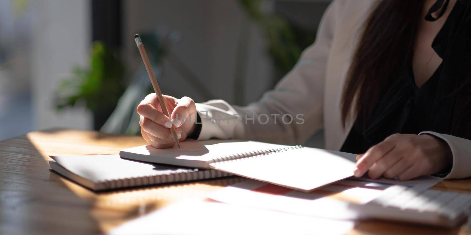Closeup view of woman hand writing on notebook with pencil. Copy space..