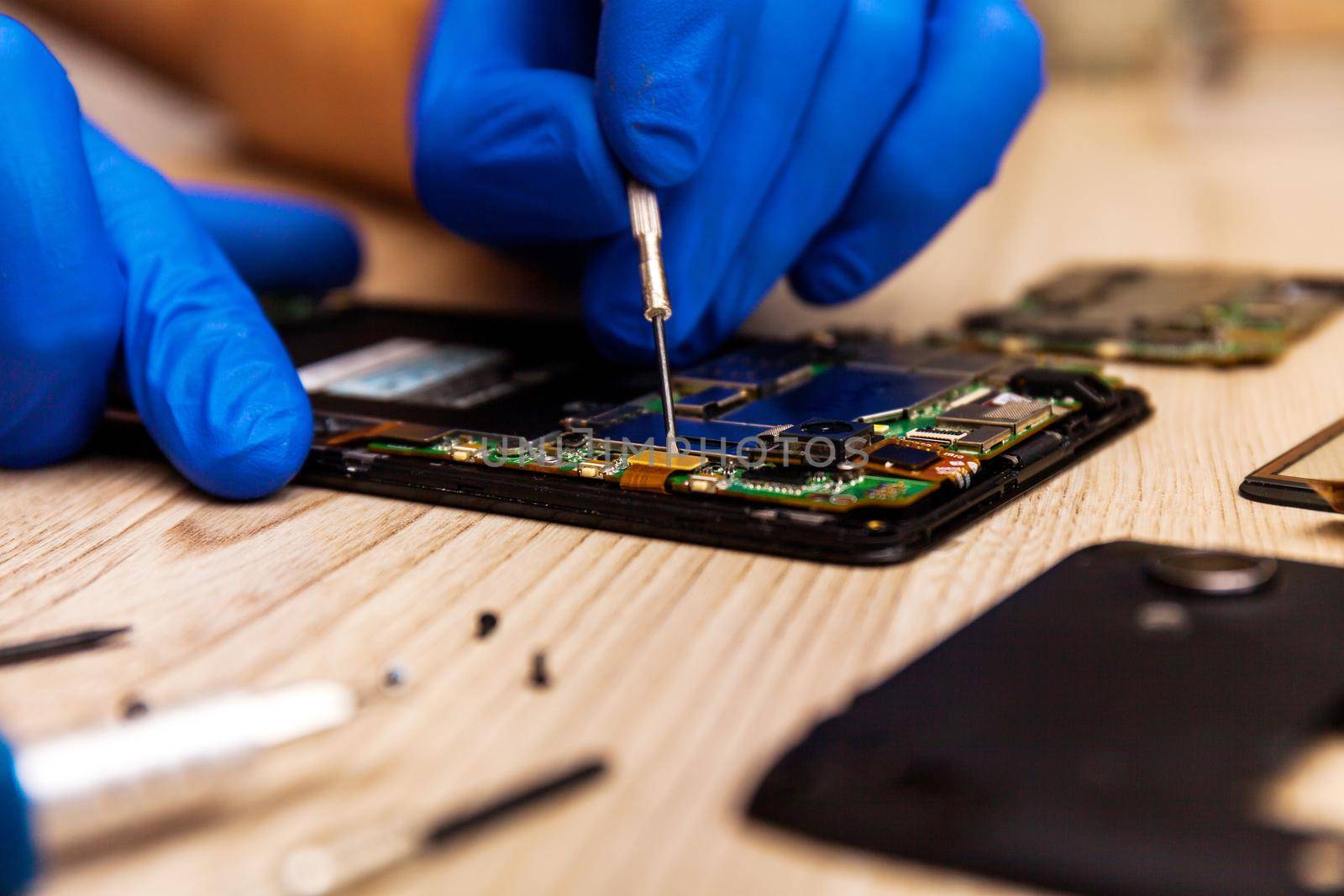 The technician repairing the smartphone's motherboard in the workshop on the table. Concept of mobile phone, electronic, upgrade and technology.