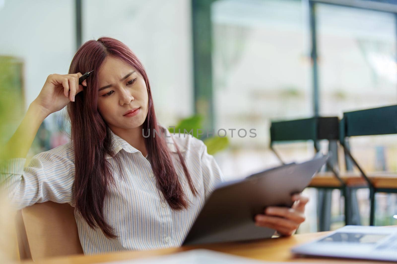 Portrait of a businesswoman holding documents and using computers to analyze budget work and make marketing plans to meet the needs of office clients.