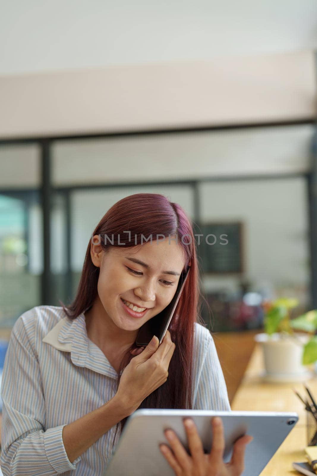 Asian businesswoman using the phone to contact a business partner by Manastrong