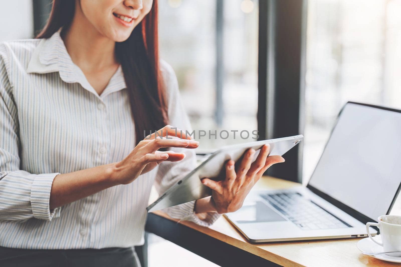 Portrait of an Asian female employee using a tablet computer to work to gather information and analyze marketing plans and investment budgets to increase company profits.