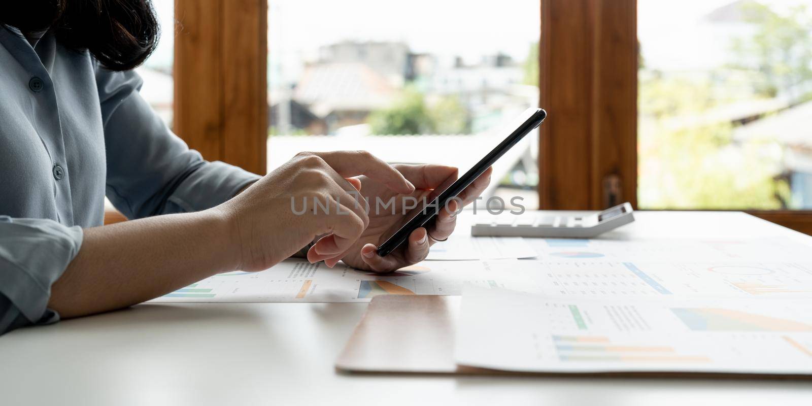 Close up hand of business woman or accountant using mobile phone and working for financaial chart graph report