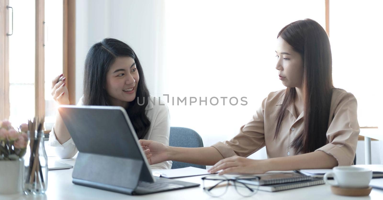 Two young Asian businesswoman discuss investment project working and planning strategy. Business people talking together with laptop computer at office..