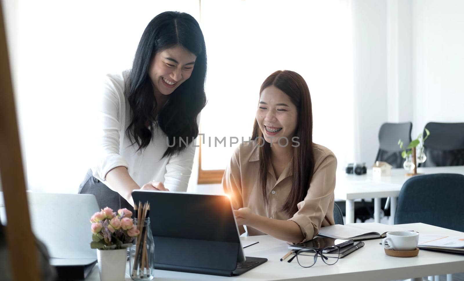 Two young Asian businesswoman discuss investment project working and planning strategy. Business people talking together with laptop computer at office..