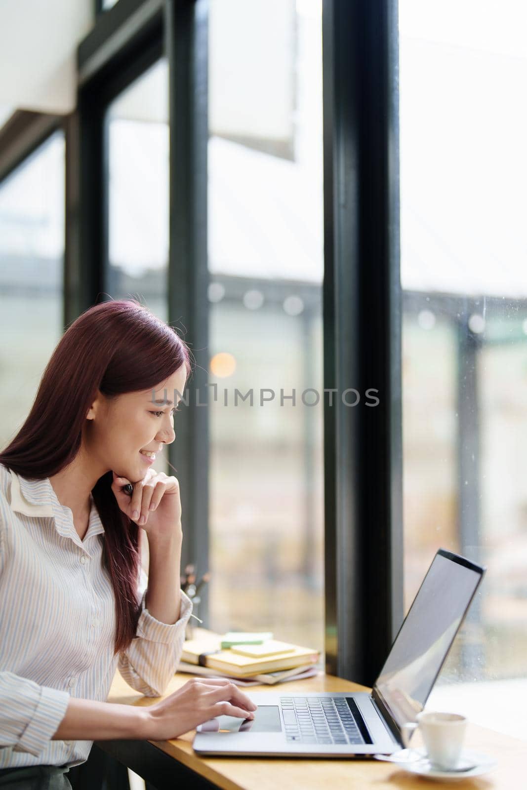 Portrait of a business woman using a computer to work on financial statements by Manastrong