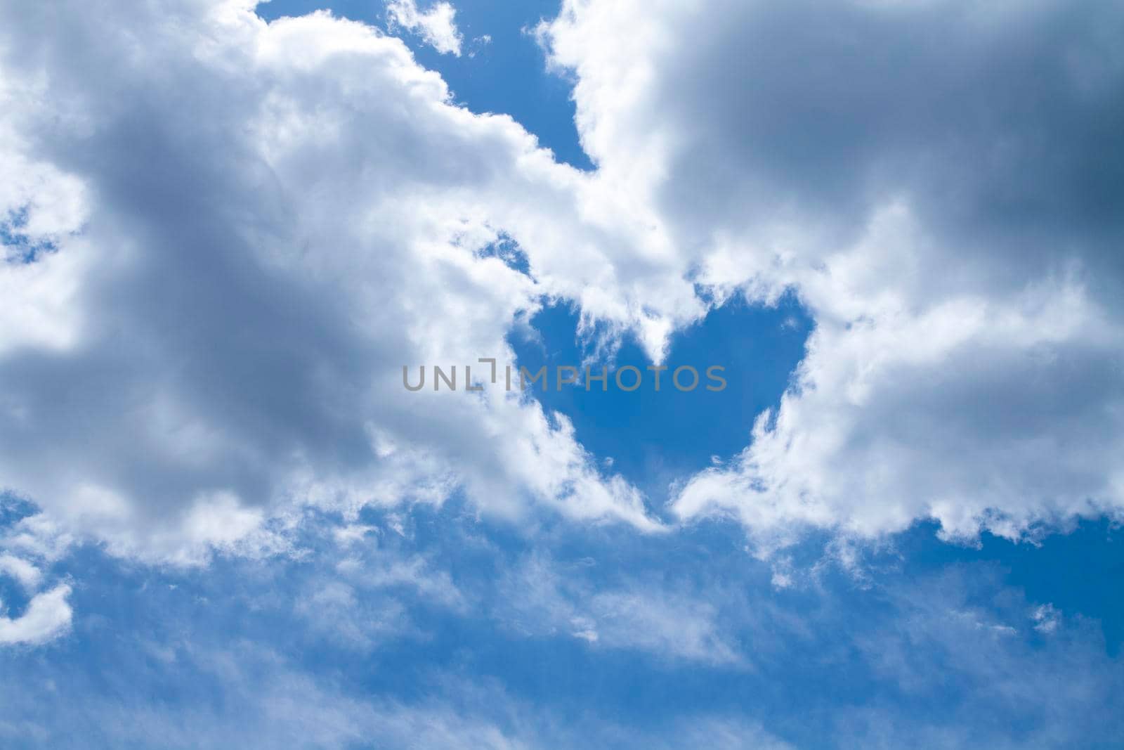 Heart shape made of white-gray clouds against a blue sky