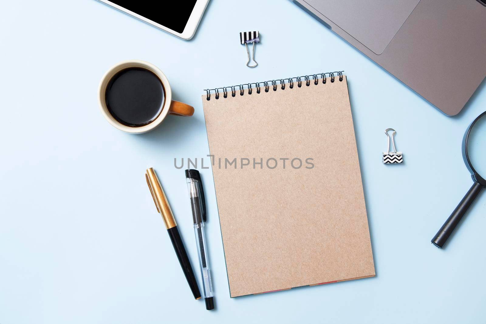 Top view workspace with a notebook mock-up, coffee, laptop on a blue background. Desktop business concept by ssvimaliss