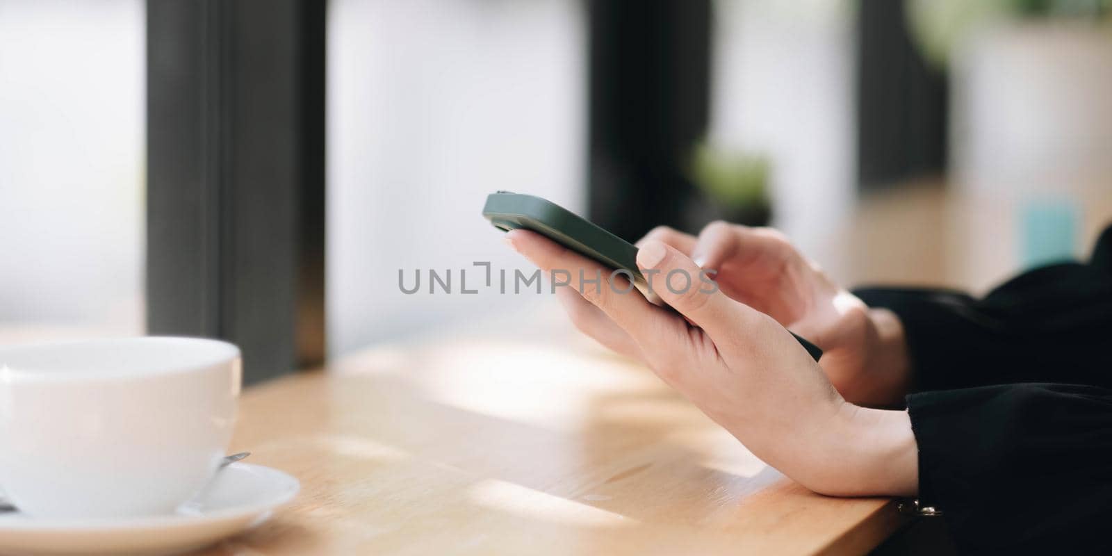 Close up of a woman using mobile smart phone at cafe. by wichayada