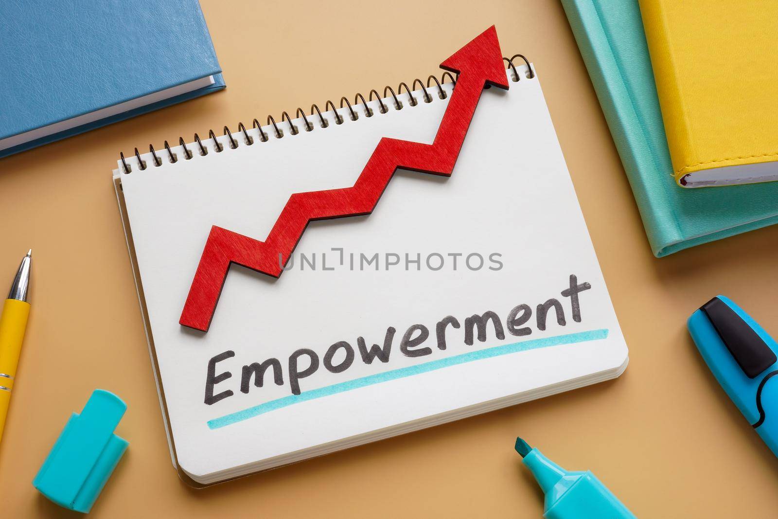 Handwritten word Empowerment and rising arrow on a notepad.