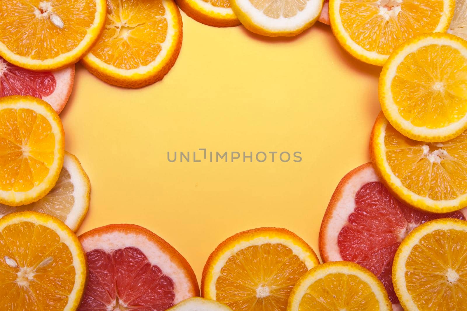 Flat lay slices of fresh orange, grapefruit and lemon formed a frame on a orange background. Bright summer concept with copy space.