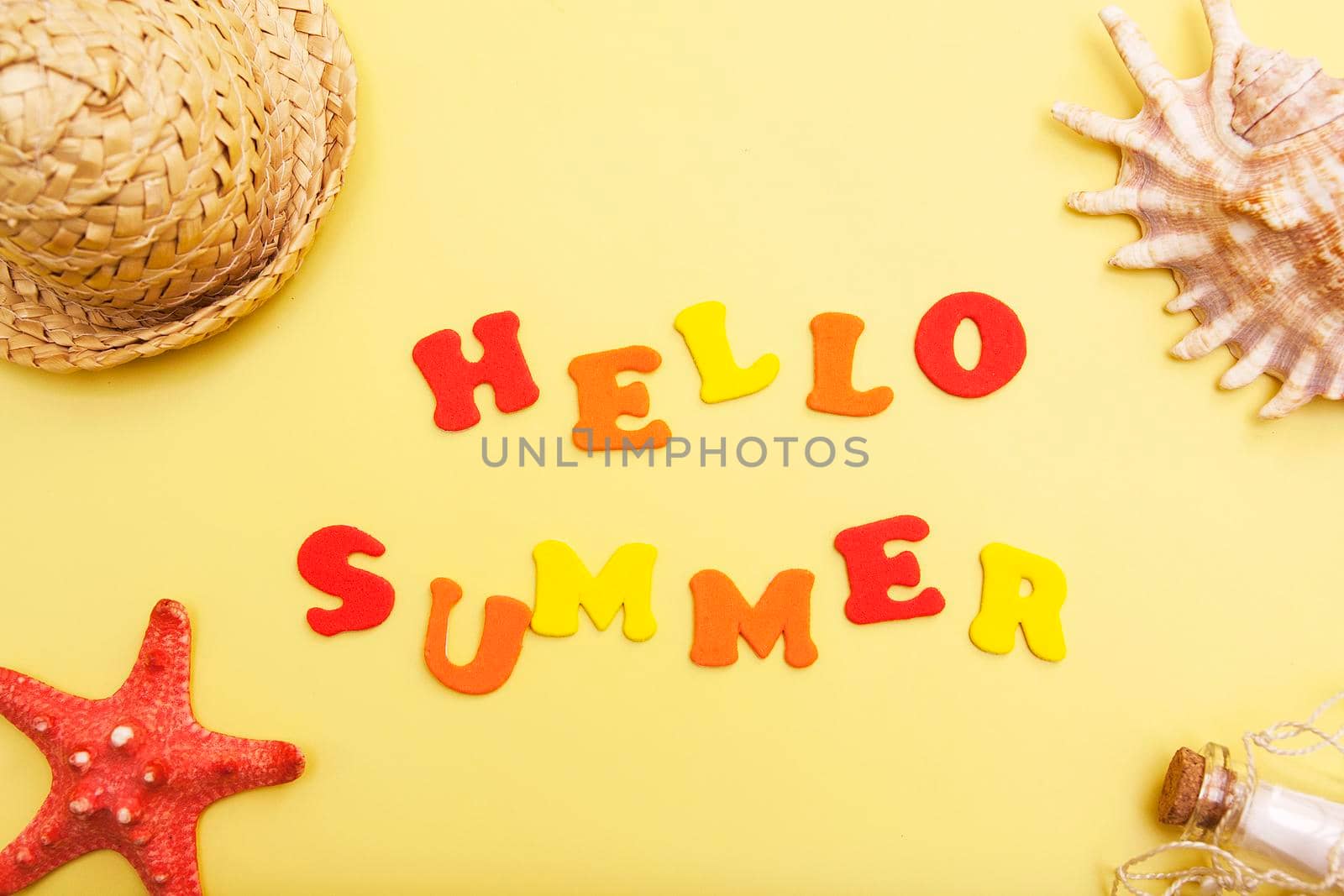 The words Hello Summer on a yellow background with a shell, hat, starfish. The concept of vacation, warmth, summer, adventure