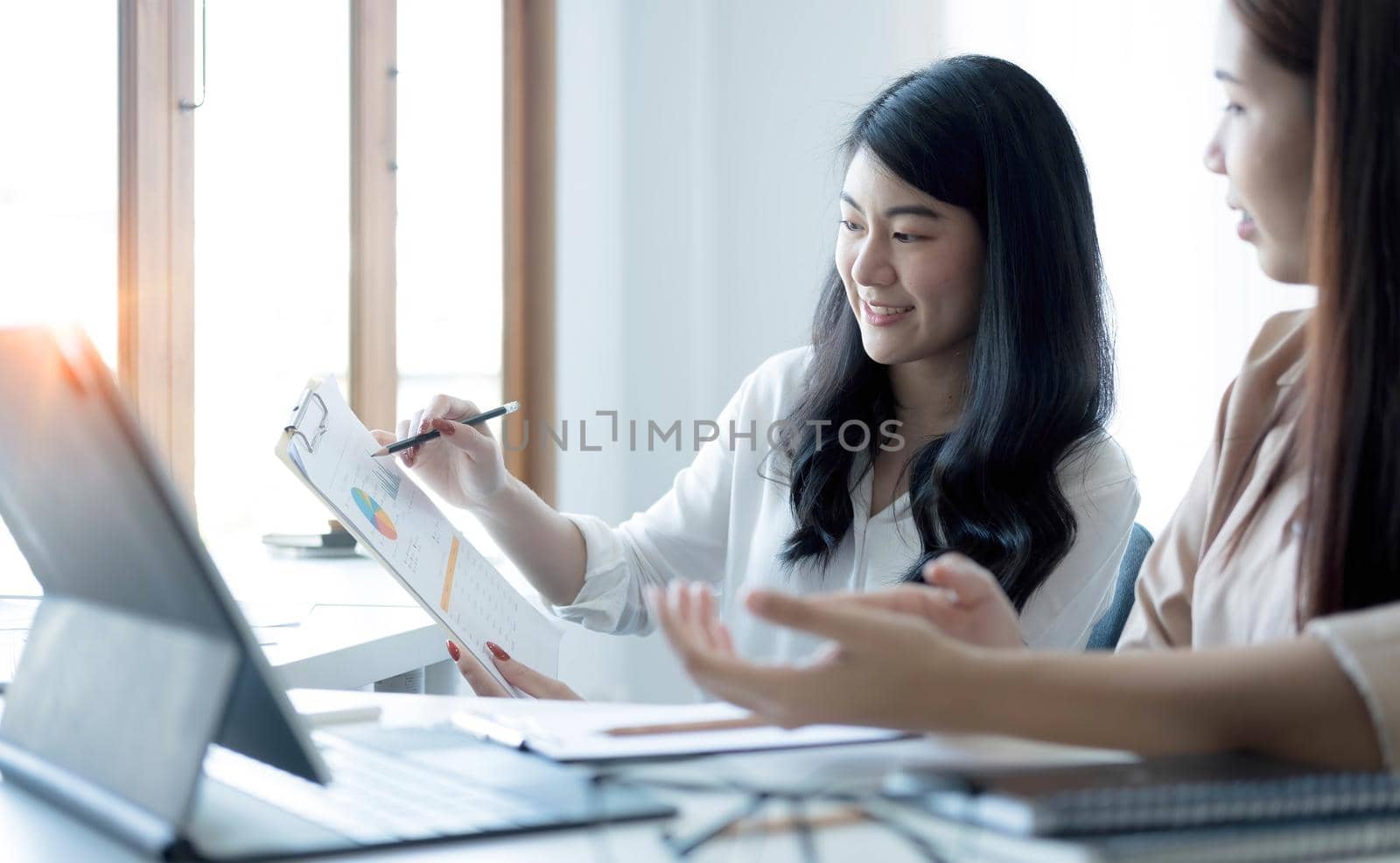 Two young Asian businesswoman discuss investment project working and planning strategy. Business people talking together with laptop computer at office..