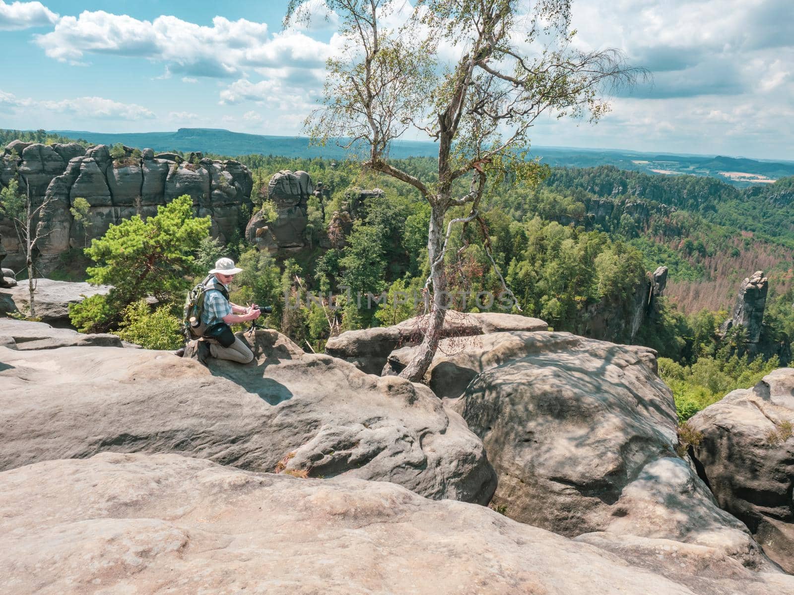Schmilka - Germany, July 06, 2022: Tourist with camera is taking photos behind the Schrammsteine rock massif, Saxon Switzerland, Germany. View from the Carolafelsen viewpoint