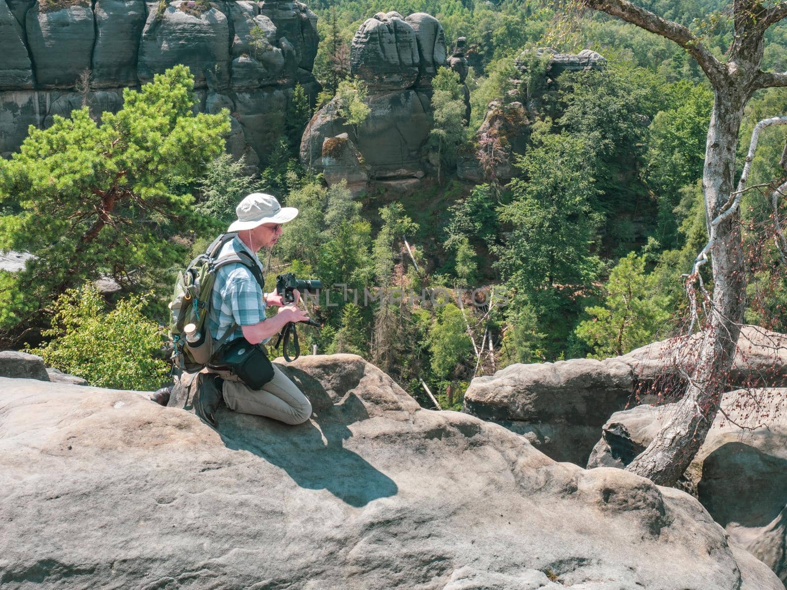 Schmilka - Germany, July 06, 2022: Tourist with camera is taking photos behind the Schrammsteine rock massif, Saxon Switzerland, Germany. View from the Carolafelsen viewpoint