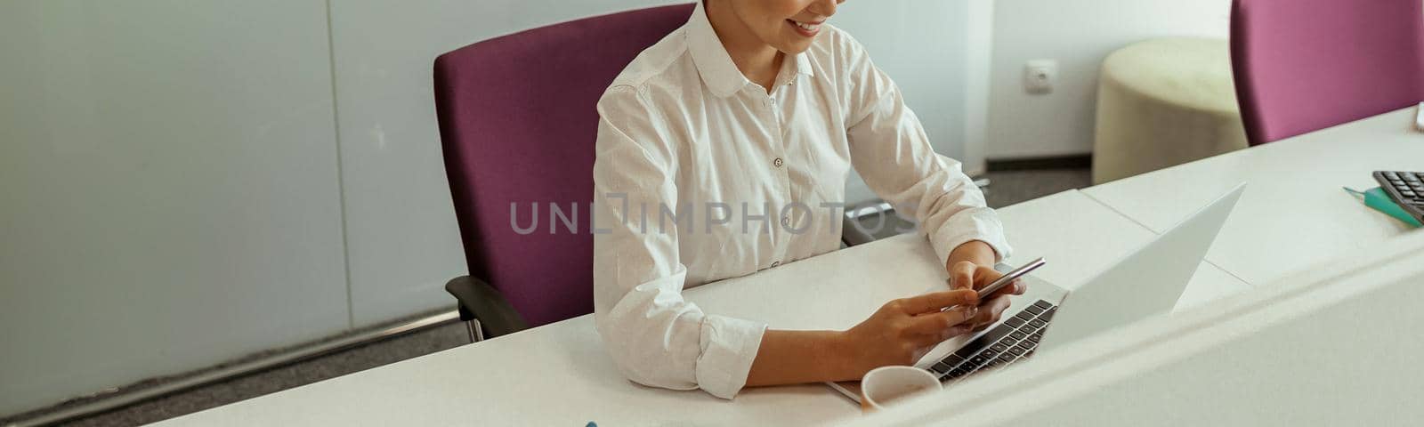 Smiling asian woman sitting in meeting room before conference and holding phone. Business concept