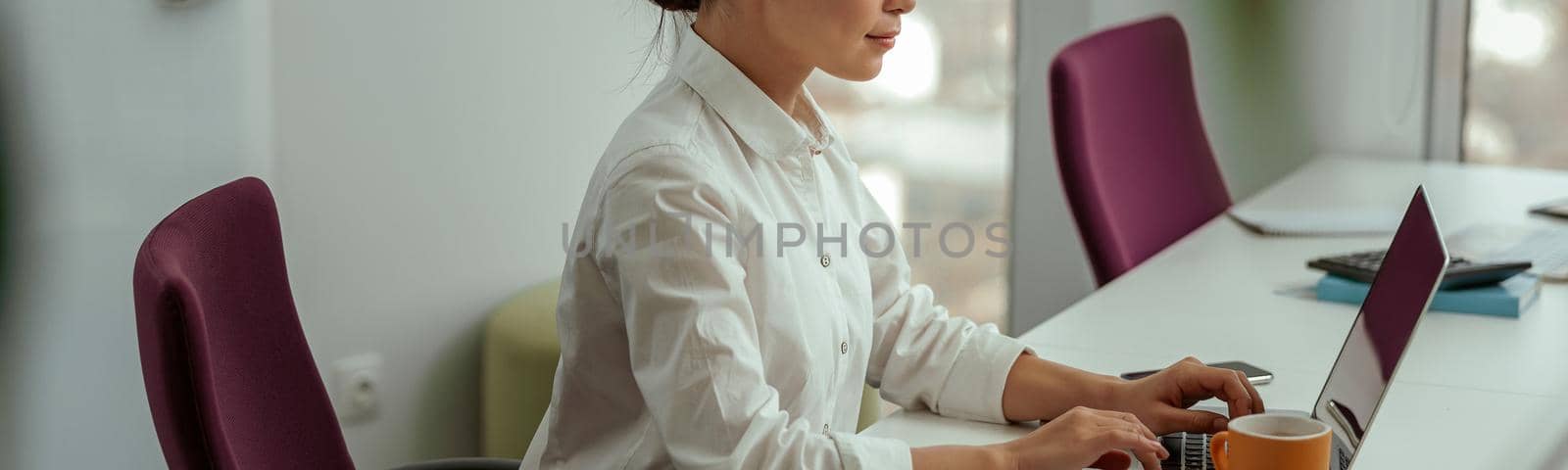 Pretty asian business woman working laptop sitting in modern office. High quality photo