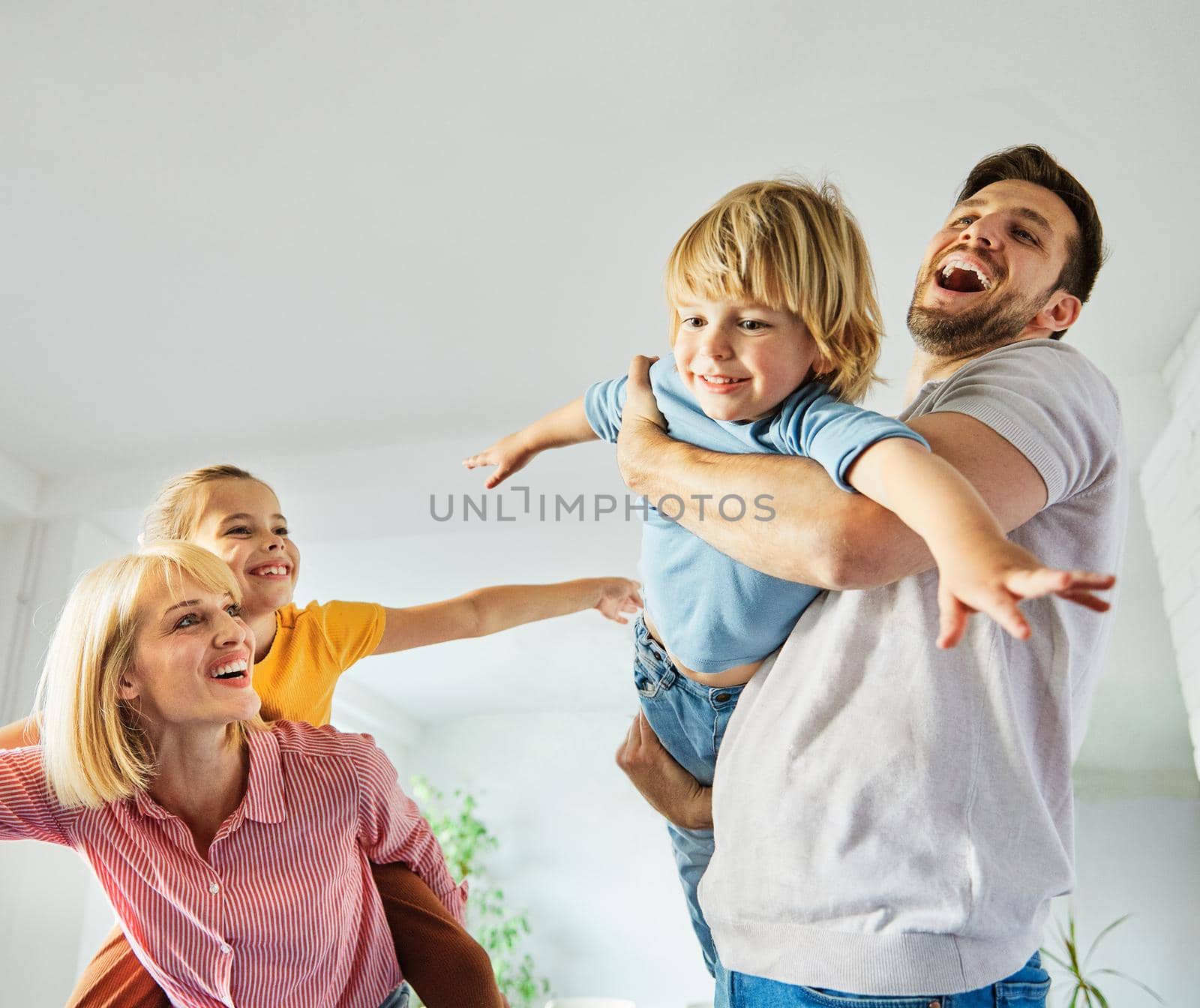 child daughter son family happy mother father sofa playing fun together girl boy cheerful smiling home together by Picsfive