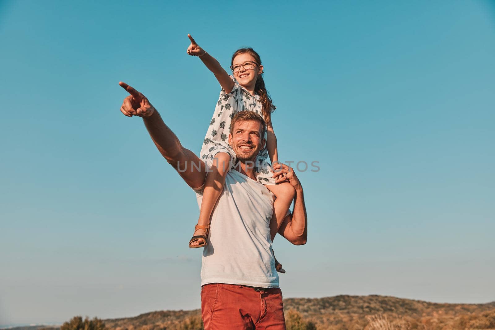 Portrait of a young happy father with his daughter having fun outdoors