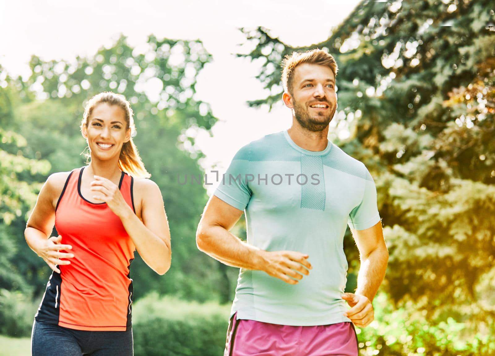 Portrait of a young couple running and exercising in a park outdoors