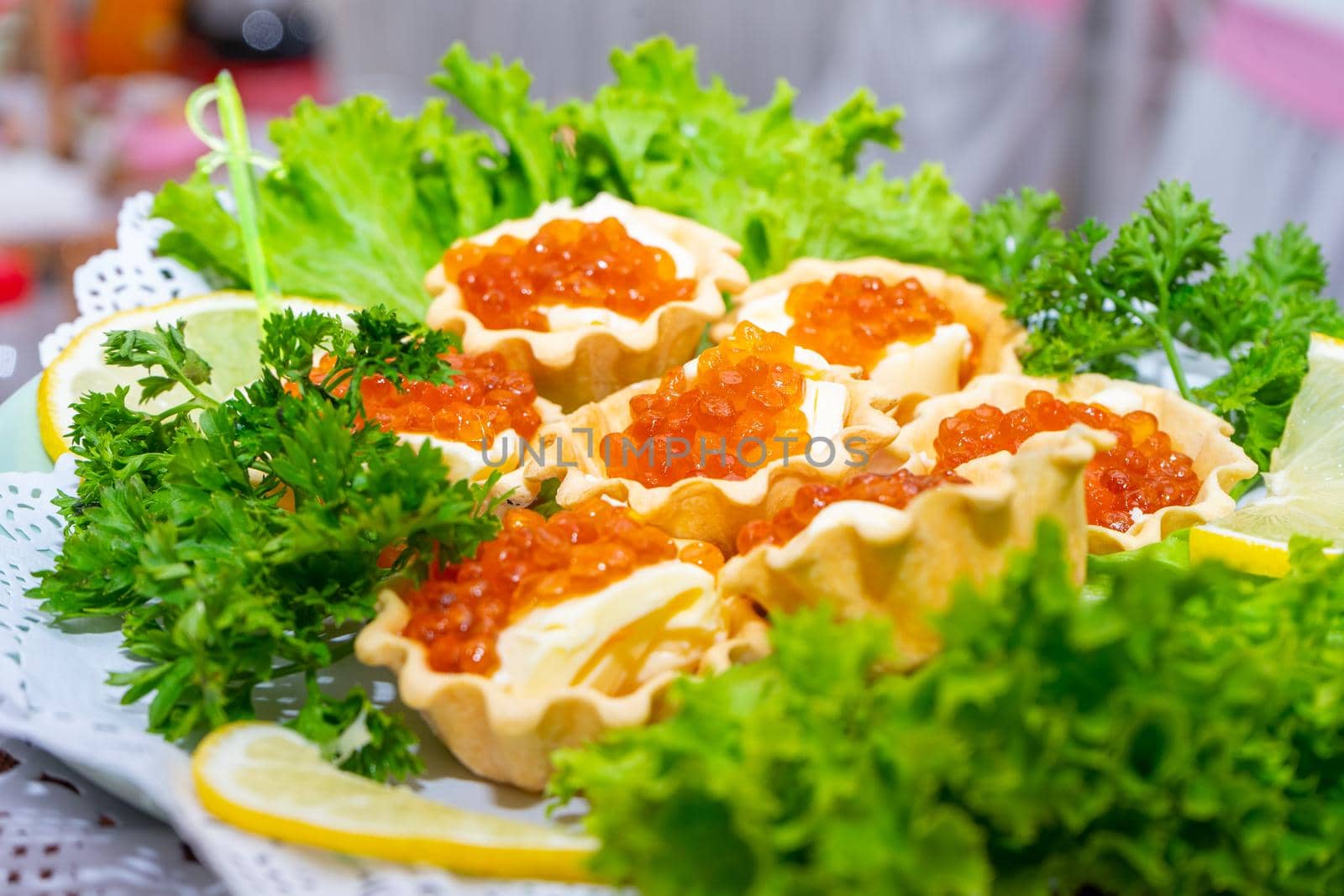 Red caviar and grated cheese in small dough baskets. A delicious cold appetizer with seafood. Close up.