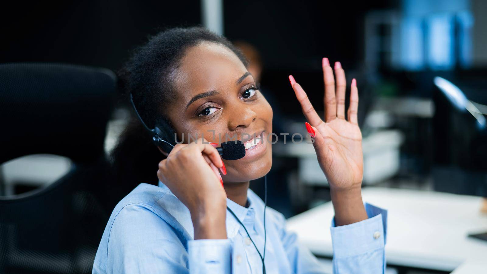 African young woman talking to a client on a headset. Female employee of the call center