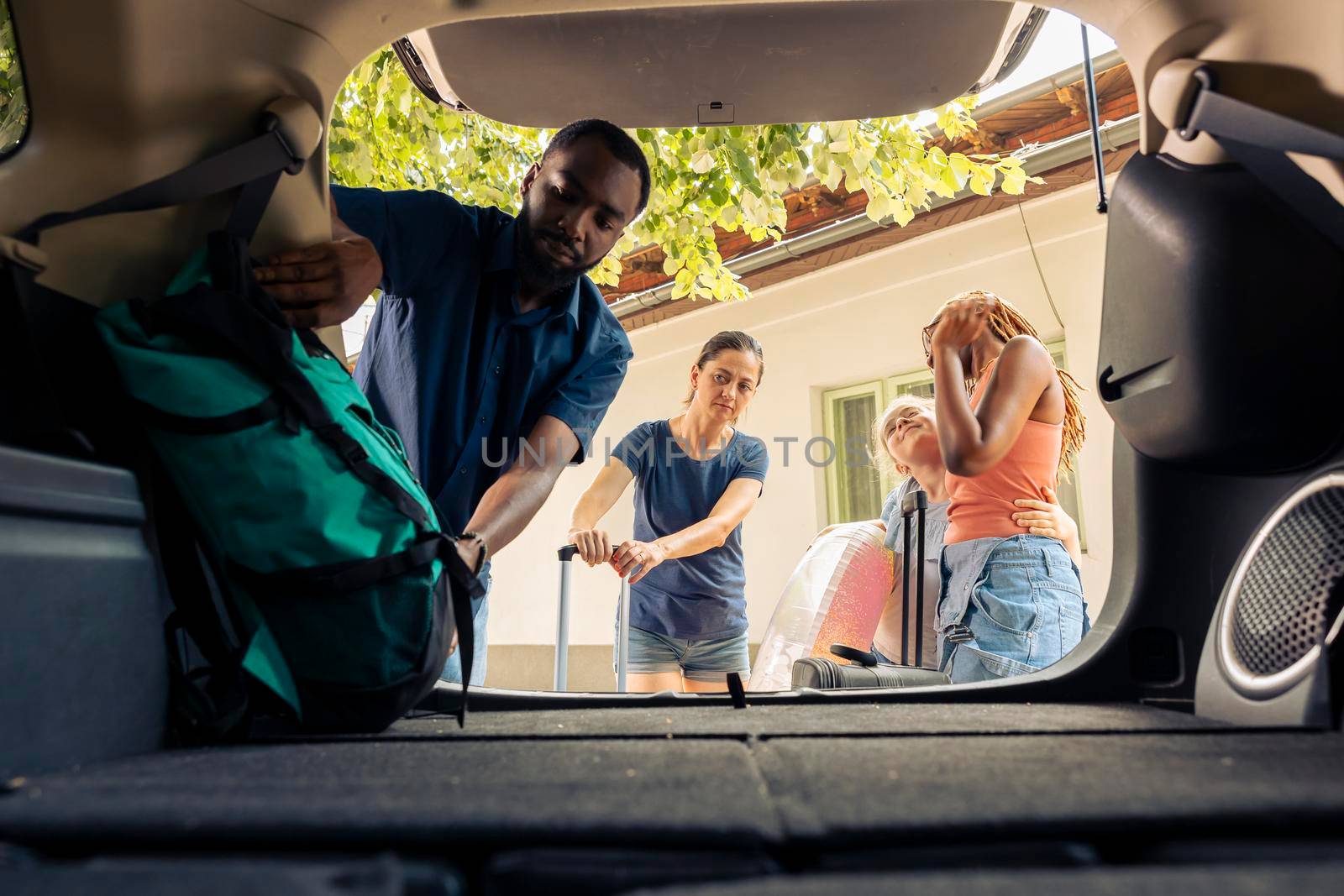 Diverse people loading luggage in trunk by DCStudio